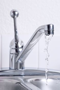 Water dribbling from a leaking faucet on the kitchen sink.