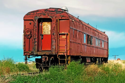 Rusted and worn out, an old passenger railcar sits on a rail siding.