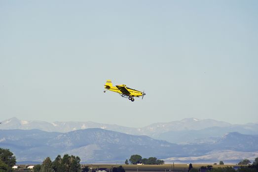 Airplane against the Rocky mtns making another run at a cornfield.