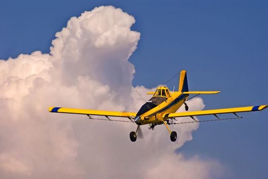 Crop duster dropping out of the clouded sky to make a spraying run on an unseen cornfield.