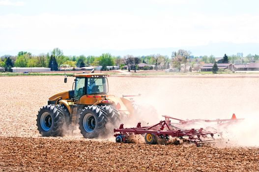 Using heavy equipment, a farmer harrows his field preparing it for the next seasons planting.