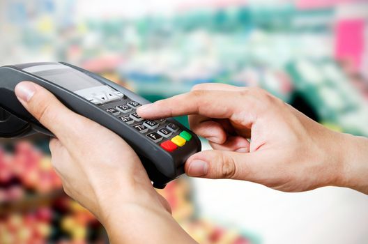 Hand with credit card swipe through terminal for sale in supermarket