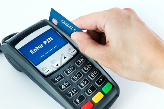 Hand with credit card swipe through terminal for sale. Enter PIN on display