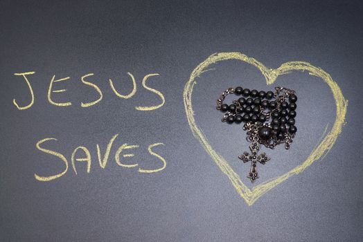 In the picture a rosary iron at the center of a heart drawn on the left side the word "Jesus saves" with a crayon