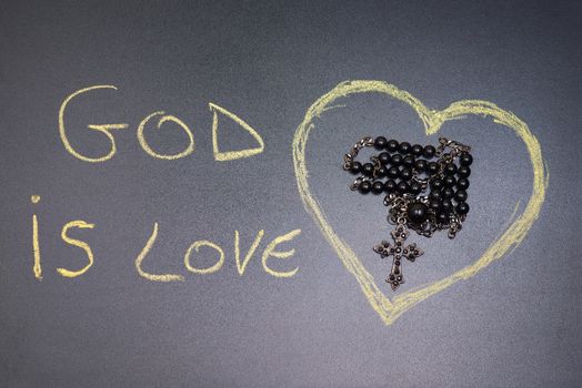 In the picture a rosary iron at the center of a heart drawn on the left side the word "god is love" with a crayon