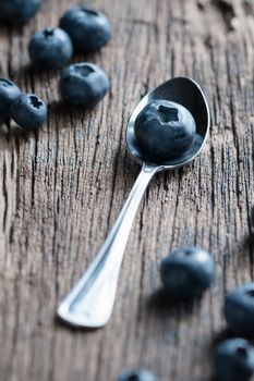 Blueberry in a spoon on wooden background