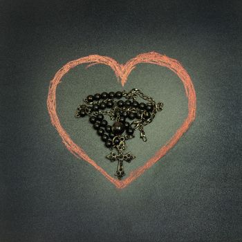 in the picture a rosary iron at the center of a heart drawn with a crayon,square photo.