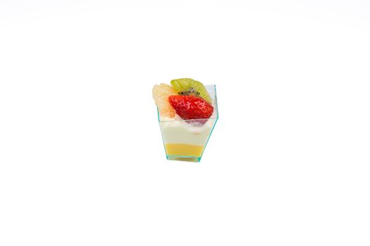 In the picture a cupcake with fruit,cream and custard in a plastic cup,isolated on white background.