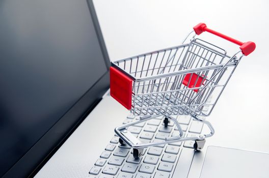 Internet shopping concept. Basket on laptop keyboard