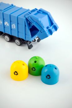 Colored trash bins and garbage truck toys on white background