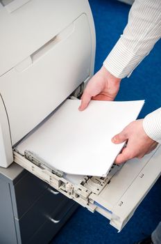 Man puts the paper in a laser printer