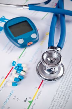 Glucometer and stethoscope on medical background