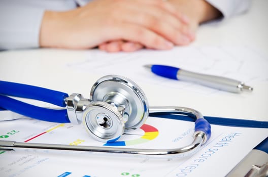 Medical doctor working at desk. Close up of stethoscope in foreground