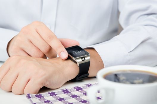 Businessman working with smart watch in restaurant. Coffee on the table 