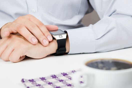 Businessman working with smart watch in restaurant. Coffee on the table 