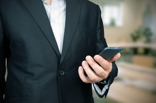 Business man in suit using smart phone in office