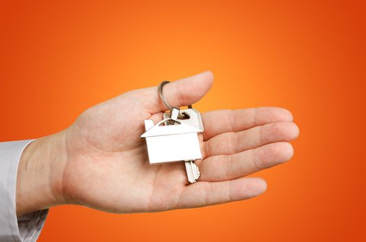 Man hand holding keys with to new house. Home shape chrome pendant 