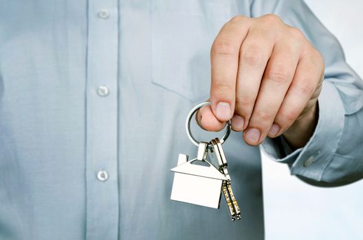 Estate agent holding keys to new house. Home shape chrome pendant 