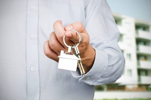 Estate agent holding keys to new house. Home shape pendant 