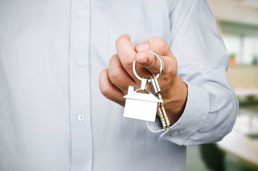 Estate agent holding keys to new house. Home shape chrome pendant 