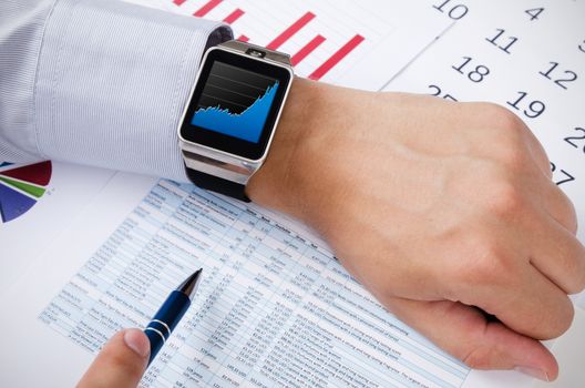 Man working with smart watch in office. Chart on screen