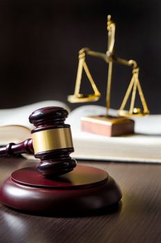 Wooden gavel and books on wooden table. Scale on books in background.