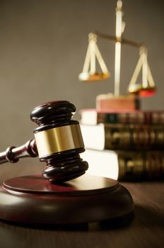 Wooden gavel and books on wooden table. Scale on books in background.