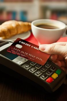 Man using payment terminal with NFC contactless technology in cafeteria