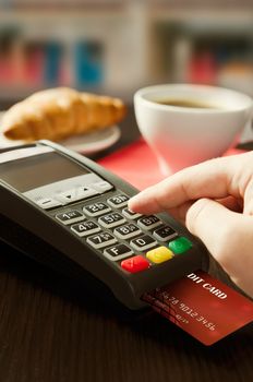 Man making payment with terminal for sale in cafeteria or restaurant