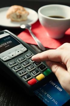 Man making payment with terminal for sale in cafeteria or restaurant