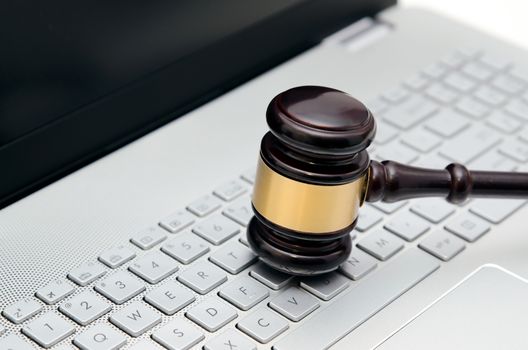 Wooden judge hammer on laptop computer white keyboard