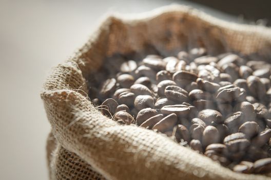 Close up coffee beans in jute bag on wooden table