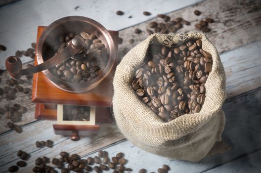 Coffee grinder with roasted beans. Vintage mill composition on wooden background