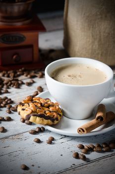 Coffee, roasted beans, mill grinder and cookie with nuts on wooden background