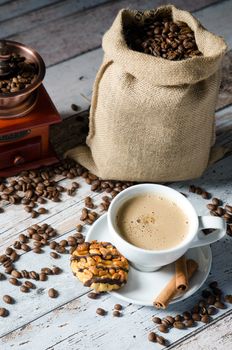 Coffee, roasted beans, mill grinder and cookie with nuts on wooden background