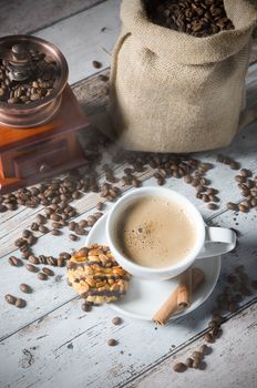 Coffee, roasted beans, mill grinder and cookie with nuts on wooden background