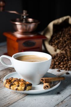 Coffee, roasted beans, mill grinder and cookie with nuts on wooden background