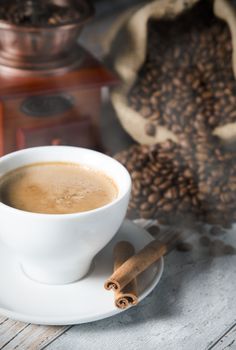 Coffee, roasted beans, mill grinder and cinnamon on wooden background