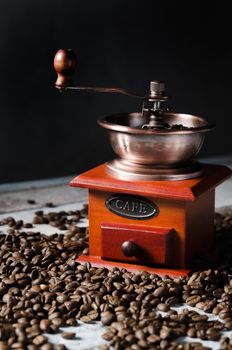 Old retro coffee grinder on wooden background with roasted coffee beans