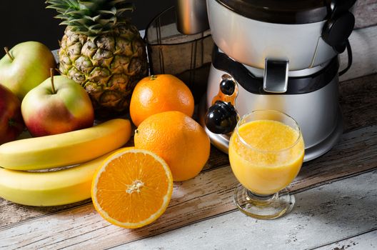Fresh juice and juicer. Photo on wooden background with lot of fruits