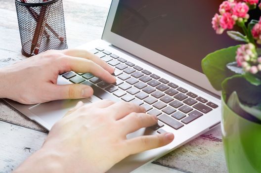 Man working with modern laptop in office. Hands typing on keyboard