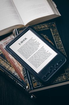 E-book reader device on desk in library. Alternative for traditional books