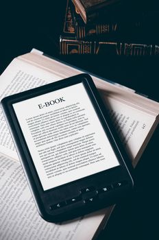 E-book reader device on desk in library. Alternative for traditional books