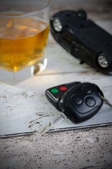 Car keys, glass of whiskey in background. Drinking and driving