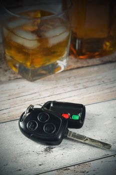 Car keys, glass of whiskey in background. Drinking and driving