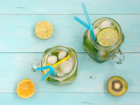 Cold homemade lemonade with fresh lemon, lime, kiwi and mint in mason jar. Summer drink on soft blue wooden background. Flat lay or top view