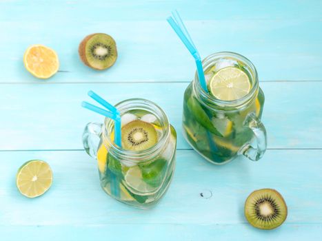 Cold homemade lemonade with fresh lemon, lime, kiwi and mint in mason jar. Summer drink on soft blue wooden background