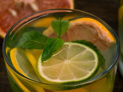 Close up cold homemade lemonade with fresh lemon, lime, grapefruit and mint. Summer drink on dark wooden background