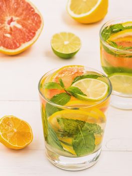 Cold homemade lemonade with fresh lemon, lime, grapefruit and mint. Summer drink on white wooden background