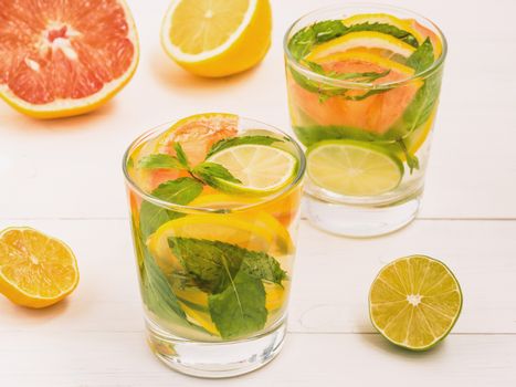 Cold homemade lemonade with fresh lemon, lime, grapefruit and mint. Summer drink on white wooden background